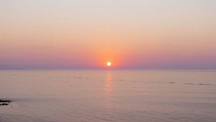 A breathtaking view of the sun setting over the ocean, casting a warm glow across the water
