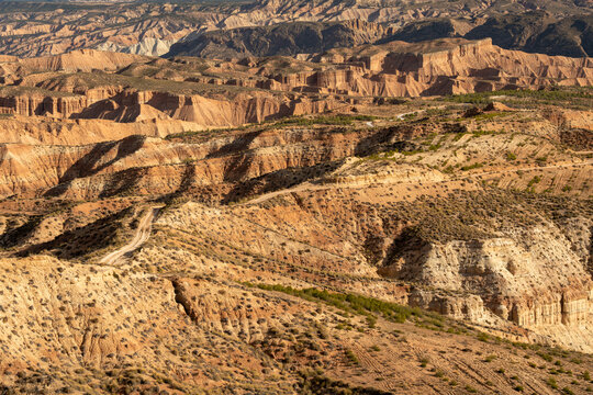 View of the undulating landscape of arid badlands, carved by time and erosion, presenting a tapestry of earthy tones and rugged textures, Gorafe, Andalucia, Spain.