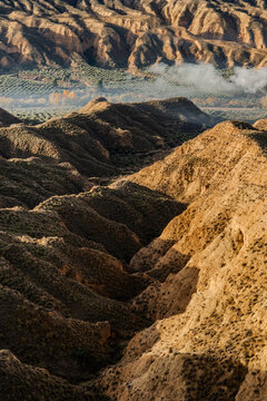 View of deep ravines carved into the earth under a blue sky creating a textured landscape in Gorafe, Andalucia, Spain.