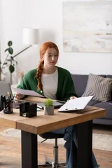 Young woman enjoying creativity and comfort in her modern home workspace © LIGHTFIELD STUDIOS