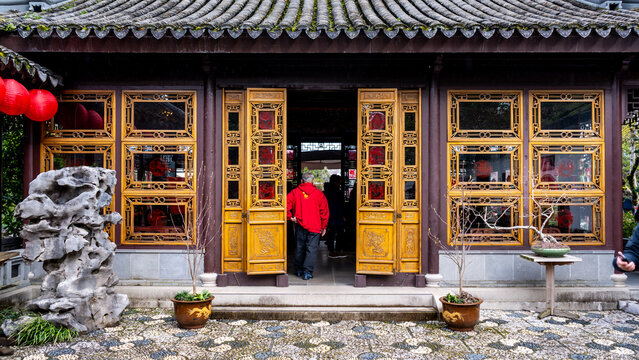 View of an ornate building with intricate wooden lattice windows and a red-clad figure entering, a scene of cultural richness, Portland, Oregon, United States.