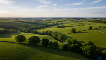 Obraz premium Lush Green Rolling Countryside with Winding River and Fields, Idyllic View