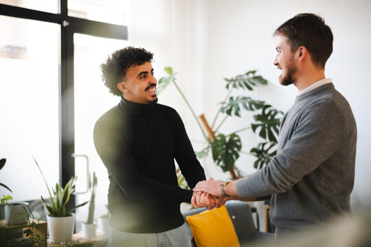 Two men shake hands in a modern office setting, symbolizing partnership and agreement.