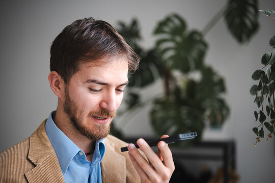 A man in a corduroy jacket and blue shirt holds a smartphone to his ear, engaged in a conversation.
