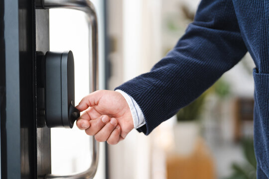 A person in a suit jacket turns a smart lock on a door, indicating access and security.