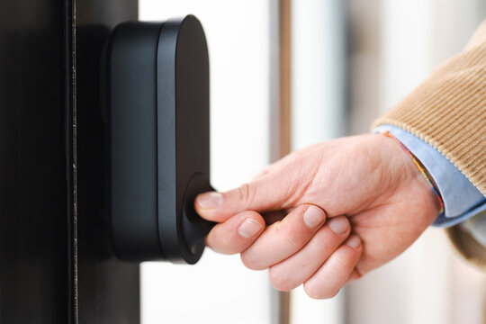 A person's hand is shown operating a smart lock on a door, indicating modern home security and access control technology.