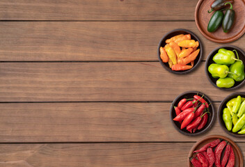 Assorted peppers over wooden table with copy space
