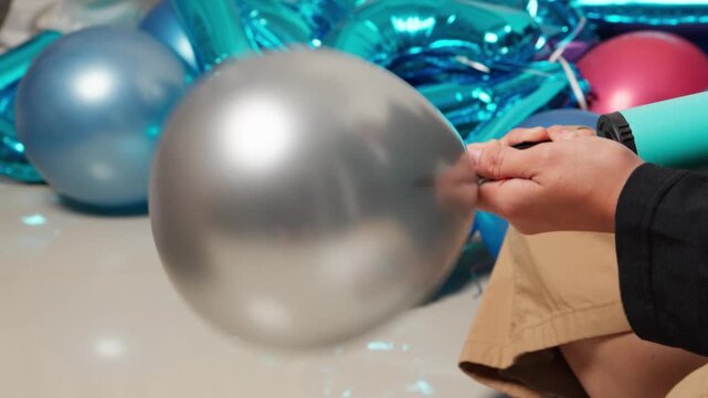 A woman is using a hand pump to inflate a party balloon