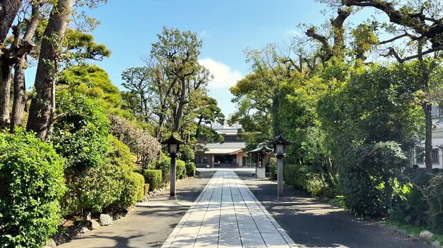 Peaceful paved path through a landscaped Japanese shrine garden