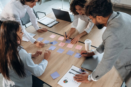 Blue and pink colored. Office workers are by the table with paper stickers, brain storming