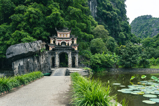 Stone bridge and ornate gate of Bich Dong Pagoda leading into a mountain cave in Ninh Binh