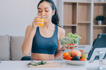 Fit young Asian women in activewear sitting on yoga mat and eating fresh vegetable salad after workout, representing clean eating, fitness lifestyle, wellness routine and health balance.