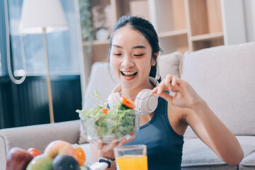Fit young Asian women in activewear sitting on yoga mat and eating fresh vegetable salad after workout, representing clean eating, fitness lifestyle, wellness routine and health balance.