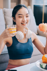 Fit young Asian women in activewear sitting on yoga mat and eating fresh vegetable salad after workout, representing clean eating, fitness lifestyle, wellness routine and health balance.