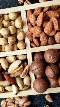 Wooden box with macadamia nuts, almonds, pistachios, and hazelnuts as ingredients for healthy eating. Nuts as a food background for your design