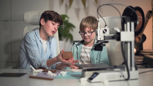 Two kids are actively discussing the parts they just printed on the 3D printer