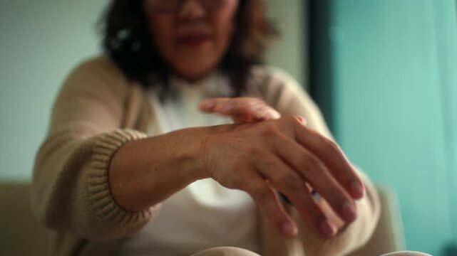 Close up elderly woman hand touching her wrist suffering pain from arthritis symptoms joint stiffness inflammation and chronic pain in retirement, healthcare insurance for wellbeing quality of life.
