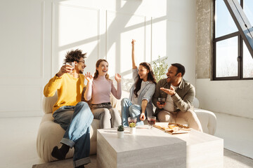 Fototapeta premium Group of happy positive diverse multinational friends drinking red wine, eating tasty pizza hands up
