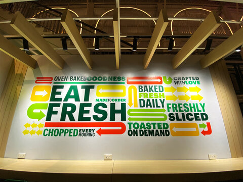 Phuket, Thailand - October 29, 2025: Colorful wall mural featuring the phrase "Eat Fresh" with various food-related graphics and slogans in a modern dining space