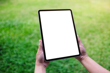 Mockup image of a woman holding digital tablet with blank desktop white screen in the green yard