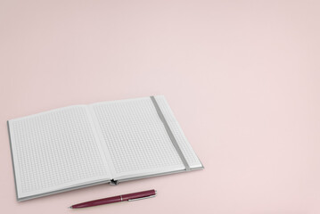 Open notebook with pen on pink background