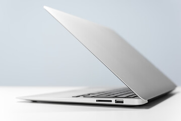 Modern laptop on white desk against blue wall