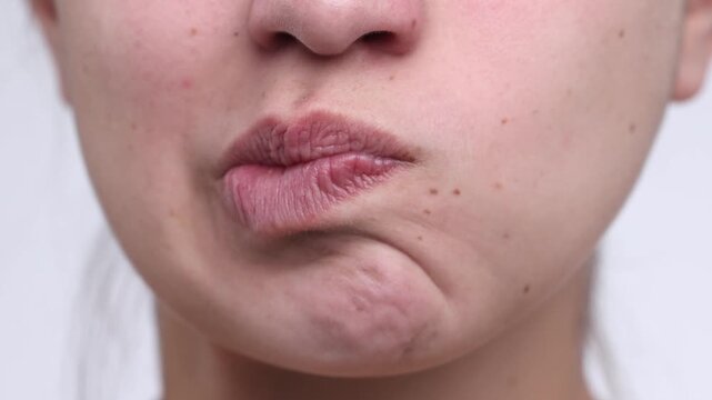 4K video macro closeup of young woman moving pressed lips left and right in insecure expression, no makeup and natural look