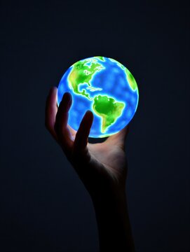 A hand holds a glowing globe depicting the Earth with vibrant colors. Global awareness and environmental consciousness.
