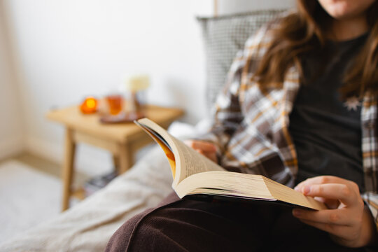 Person relaxing on bed reading book at home