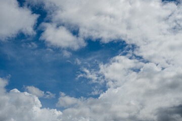 Obraz premium Patch of blue sky surrounded by dense white and grey clouds