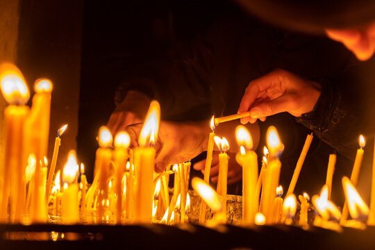 Many hands of people light and place candles in church, leaving numerous burning candles at Christian altar. Believers pray for forgiveness and help Prayer and sacred rituals Religion and faith in God