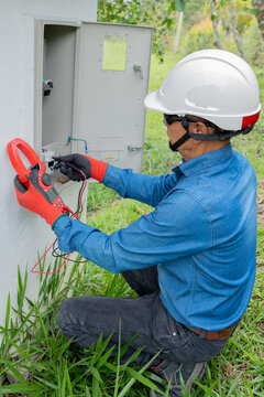 Professional electrician using a clamp meter to measure the flow of electric current. vertical