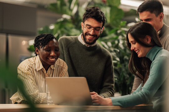 Diverse startup team collaborating on laptop computer