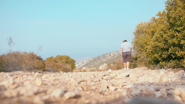 Active Woman Exploring Rocky Terrain in Mountains During Sunny Weather Adventure Journey