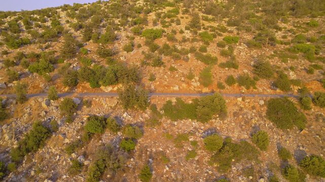 Plus Size Female Exercising in Nature by Running on Road Among Scenic Mountains at Dusk, drone view