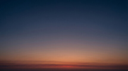 Fototapeta premium Smooth gradient sky transitioning from deep blue to warm orange and red hues capturing the serene atmosphere of dawn or dusk