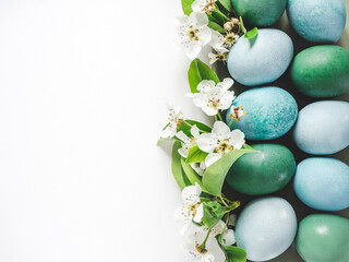 Pastel blue Easter eggs on a white table with spring blossoms. Festive Easter and spring...