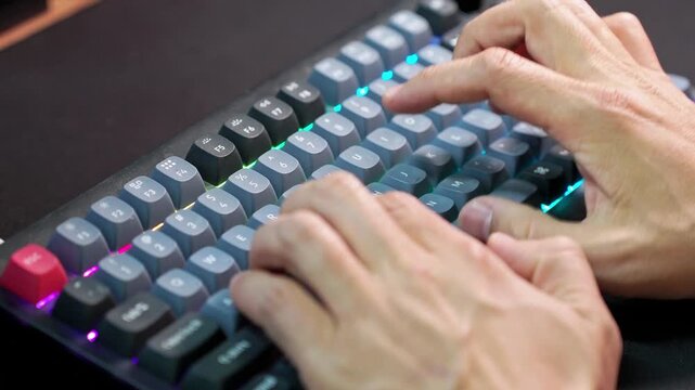 Close-up of hands typing on illuminated mechanical keyboard with RGB backlight. Concept of programming, gaming, remote work, digital productivity and modern technology workspace.