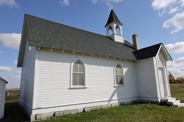 tiny rural wooden church under partly-cloudy deep blue skies (historic, side-view, wide-angle, panorama)