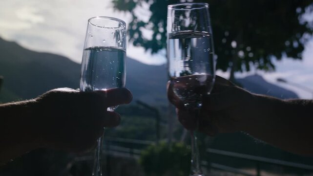 Romantic Champagne Toast with Glasses Clinking in Front of Scenic Sunset Mountains