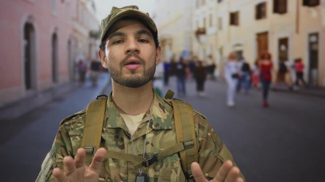 Hispanic man in camouflage combat uniform with dog tags raising palms forward on busy street; caution.