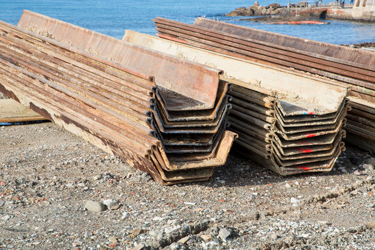 STEEL SHEET PILING STACKED AT CONSTRUCTION SITE - Metal sheet pile elements for excavation, retaining wall, shoring and foundation work in civil engineering and infrastructure project