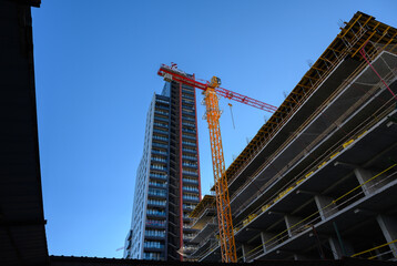 Naklejka premium Bright Yellow Tower Crane over Active Construction in Sunlight