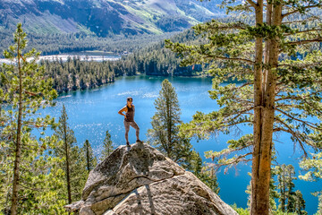 A woman stands on a rock overlooking a lake © ExploringandLiving
