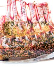 Marinated rack of lamb in vacuum pack for extra freshness. Premium top quality lamb meat on white background. Butcher craft and skill. Modern technology to keep the product flavor.