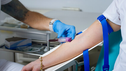 A healthcare worker performs a blood draw from a patients arm using sterile tools in a clinical...
