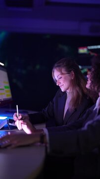 Senior software developers debugging complex backend cloud infrastructure code. Female data science engineers reviewing predictive AI algorithms on digital tablet and monitor.