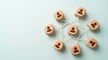 Wooden blocks with human silhouettes connected together by string on teal background, illustrating teamwork, business networking, community connections, collaboration and organizational relationships