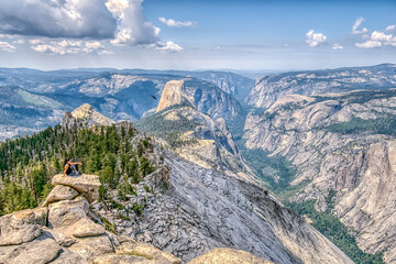 A person is sitting on a rock in the mountains