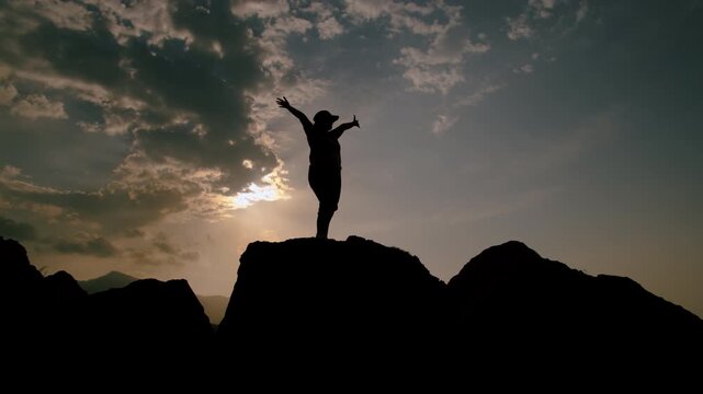 Happy Woman with Arms Raised Standing on Mountain Peak at Sunset Admiring Scenic Horizon